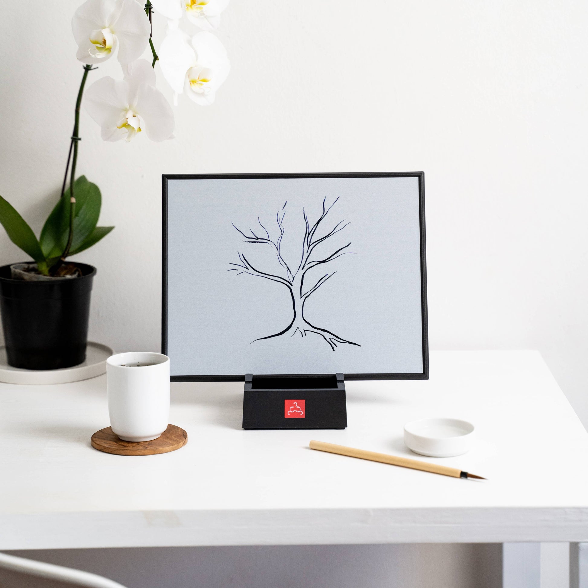 Digital display on a desk with a tree illustration, a cup, and a plant.