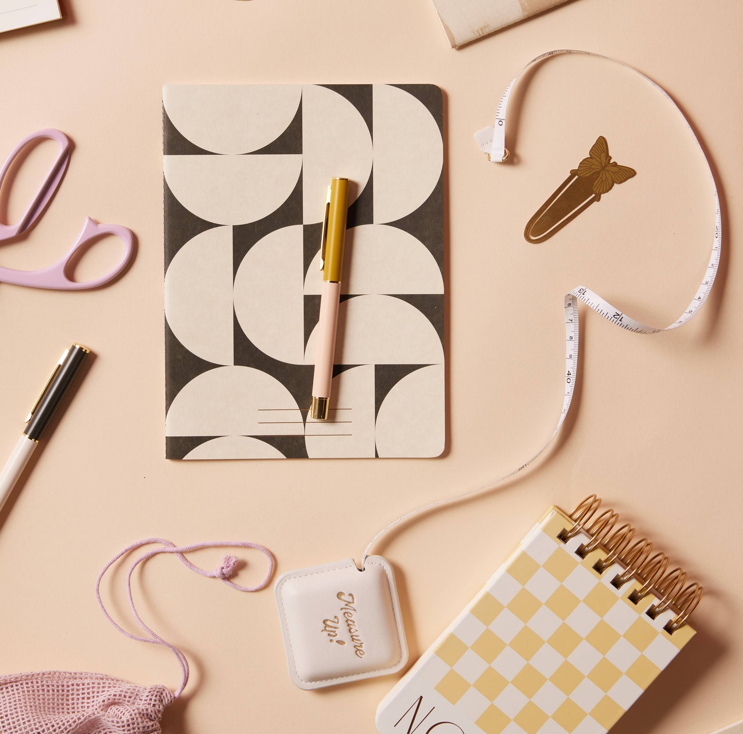 Notebooks, pens, and decorative items on a beige surface