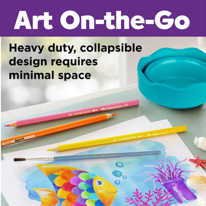 Art supplies including colored pencils and a painting of a fish on a table with a blue container.