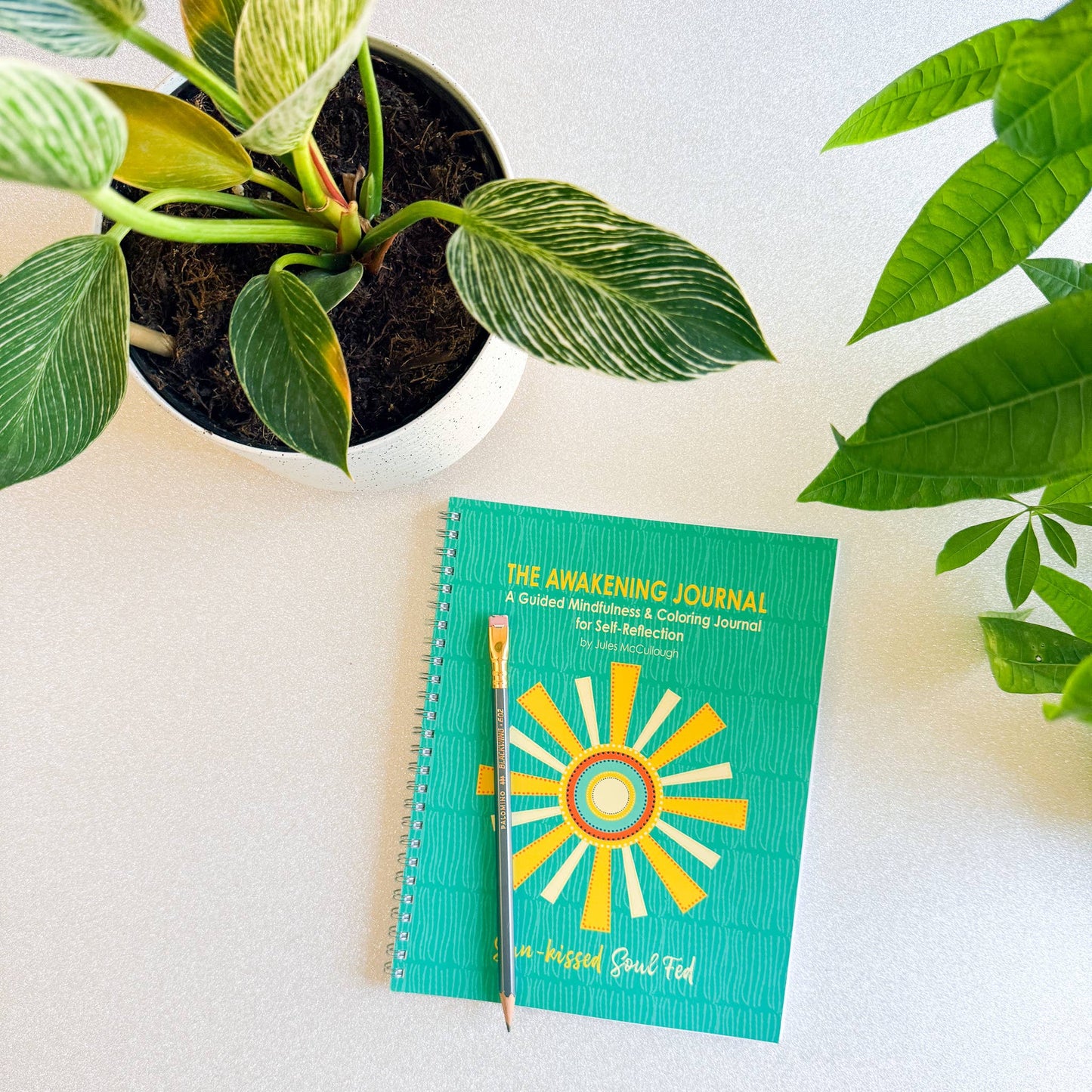 Green journal with sun design on a white surface with plants