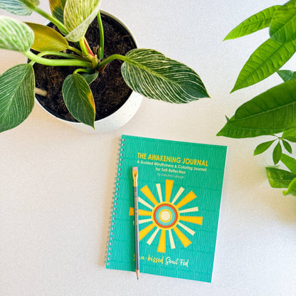 Green journal with sun design on a white surface with plants