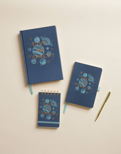 Three blue notebooks with 'Give Me Space!' design on a beige background