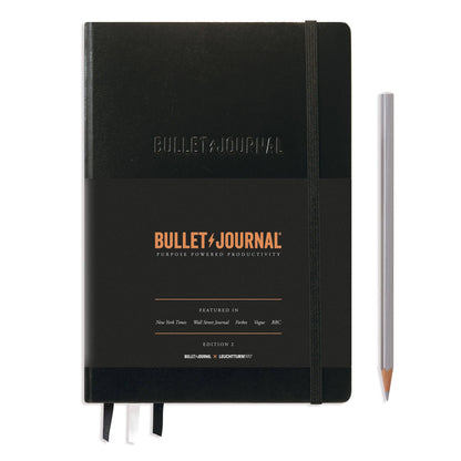 Black Bullet Journal notebook with a pencil on a white background
