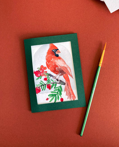 Card with a red cardinal illustration on a red background with a paintbrush.