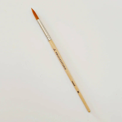 Paintbrush with wooden handle and silver ferrule on a light gray background