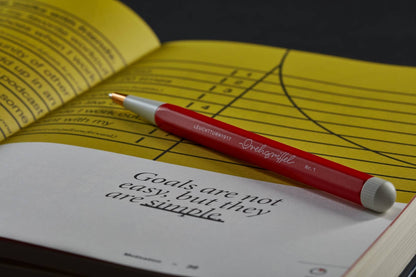 Red pen on a yellow book with a motivational quote
