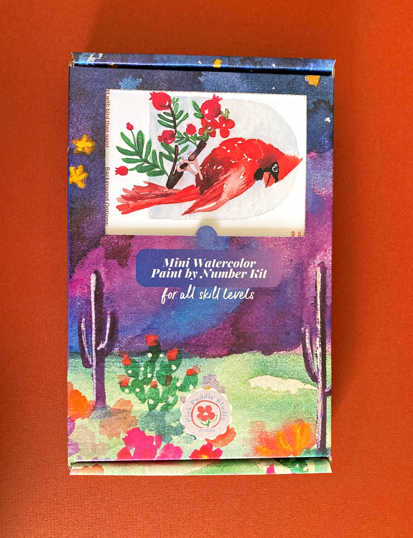 Mini watercolor paint by number kit with a colorful design on an orange background