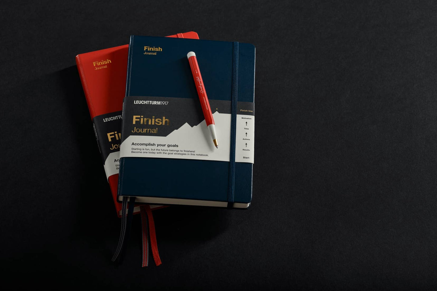 Stack of Leuchtturm journals with a pen on a dark background