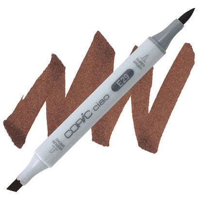 A double-ended Copic Ciao marker with a brush tip on one end and a medium broad tip on the other, with a swatch of burnt umber color in between.