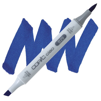 Copic Ciao marker in ultramarine color with a double-ended design, showing the tip of the marker on a blue textured surface.