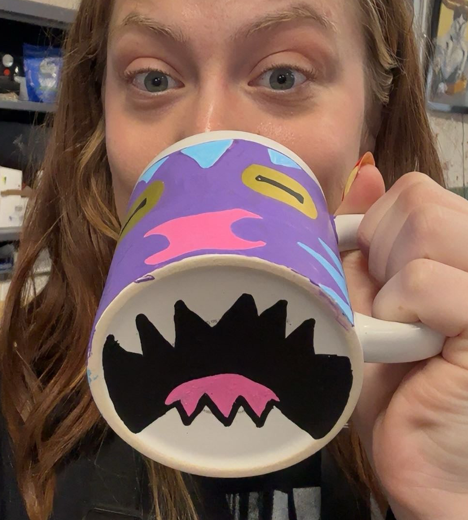 Person holding a colorful mug with a shark design