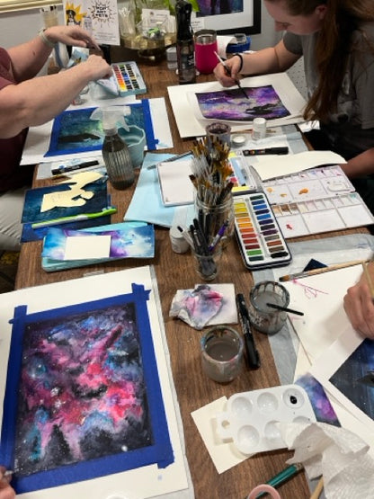 Artistic workshop with participants painting abstract artworks on a table.