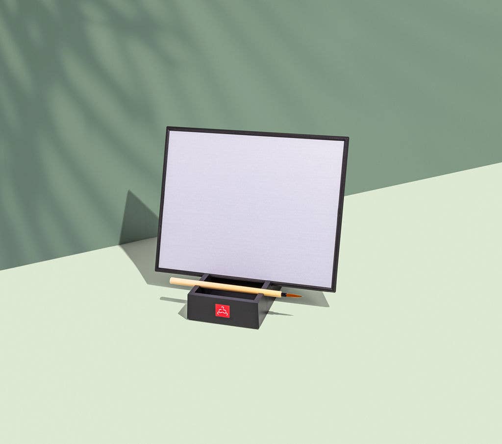 Small screen device on a stand with a pen on a light green surface and background