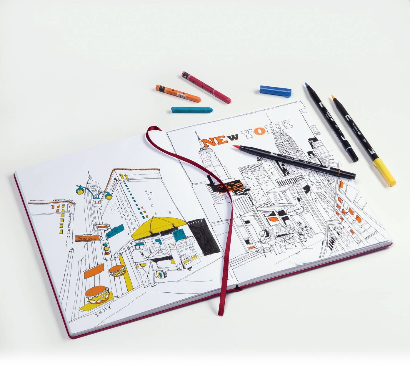 Coloring book with New York City illustration and markers on a white background