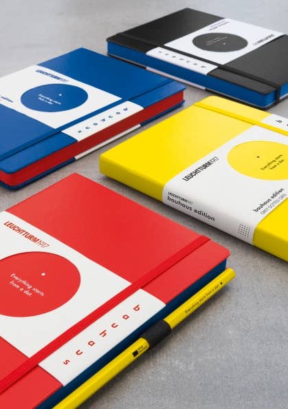 Three notebooks with colorful covers and geometric designs on a gray surface