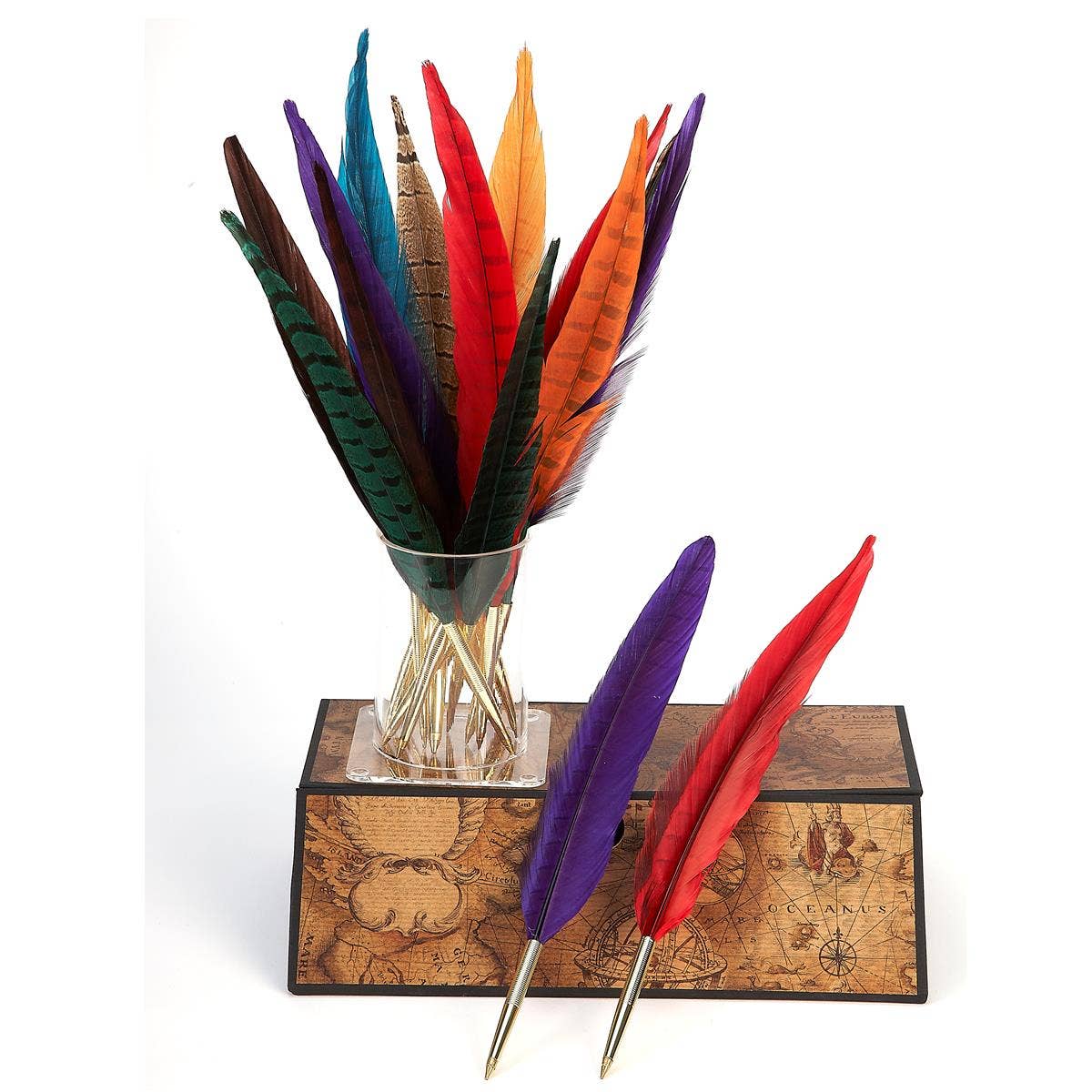 Colorful feathers in a glass vase on a decorative wooden box with a white background